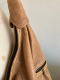 Textured tan leather bag on a mannequin against a white background