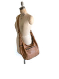Textured tan leather bag on a mannequin against a white background