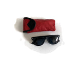 Black sunglasses with a red and black case on a white background