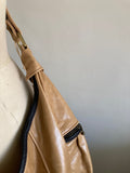 Smooth tan handbag on a mannequin against a white background